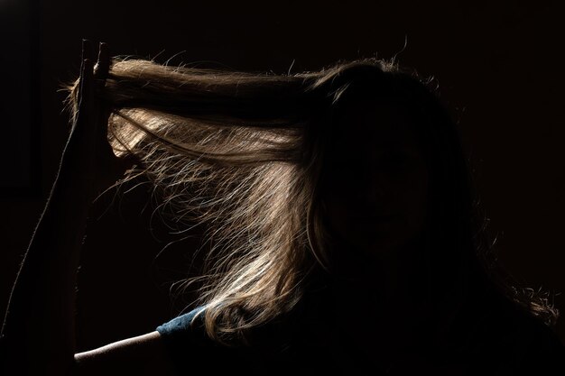 Silhueta de mulher que está tocando seu cabelo longo e reto