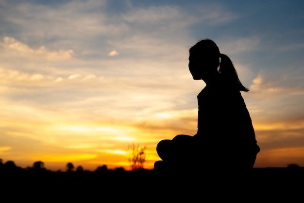 Silhueta de mulheres tristes e deprimidas sentadas na passarela do parque com o pôr do sol