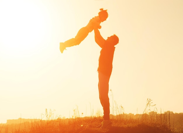 Silhueta de pai vomitando sua filha no céu ao pôr do sol