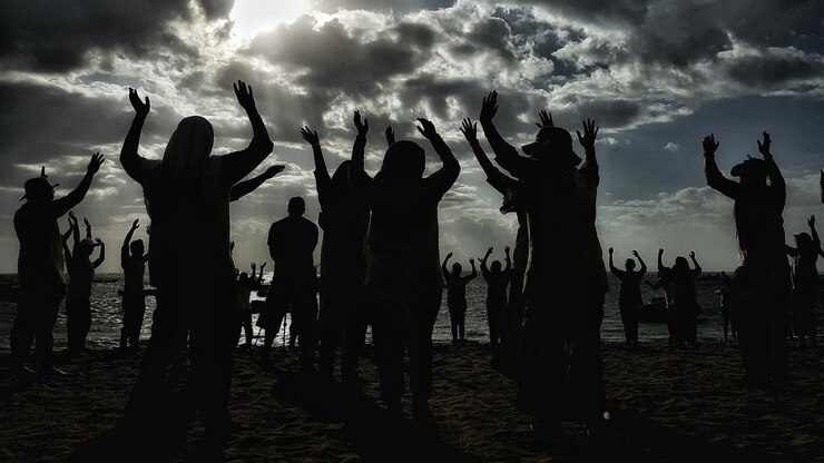 Foto silhueta de pessoas com os braços levantados de pé na praia