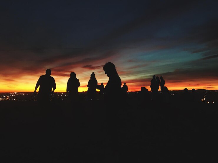 Foto silhueta de pessoas contra o céu laranja durante o pôr-do-sol