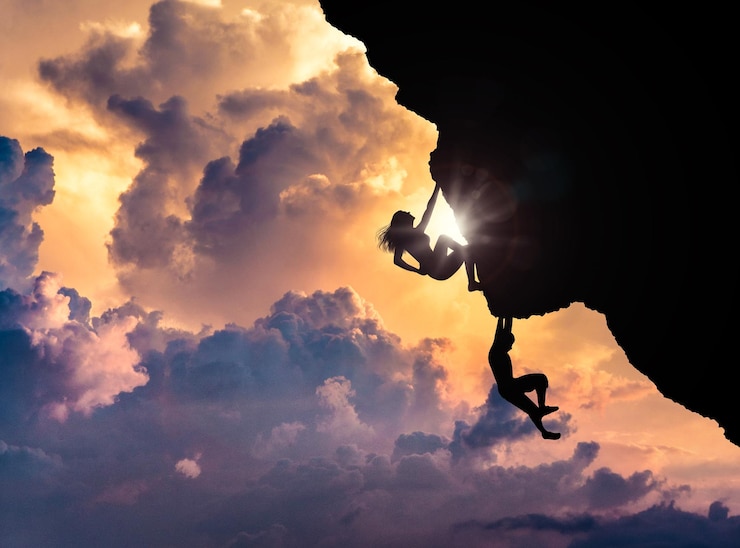 Foto silhueta de pessoas escalando rocha contra o céu ao pôr-do-sol