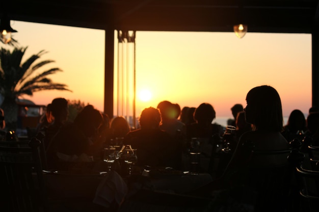 Foto silhueta de pessoas sentadas em um restaurante durante o pôr do sol