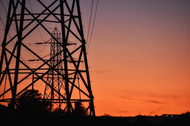 Silhueta de pilares elétricos contra o céu durante o pôr do sol