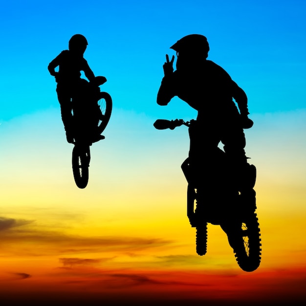 silhueta de piloto de motocross saltar no céu ao pôr do sol