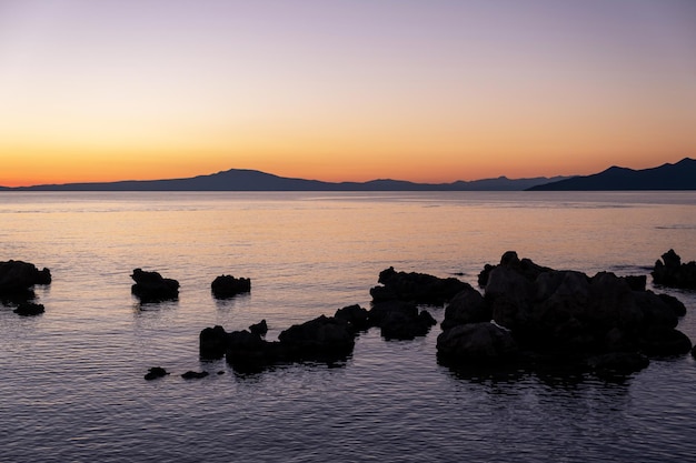 Foto silhueta de rocha no céu da cor do pôr do sol do mar stoupa beach em mani messenia grécia peloponeso