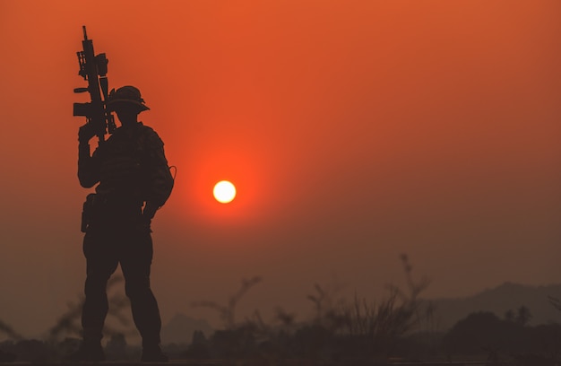 silhueta de soldado no céu pôr do sol. soldado com patrulha metralhadora