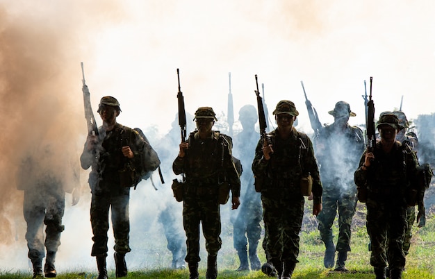 Foto silhueta de soldados não reconhecidos com rifle andar através da fumaça