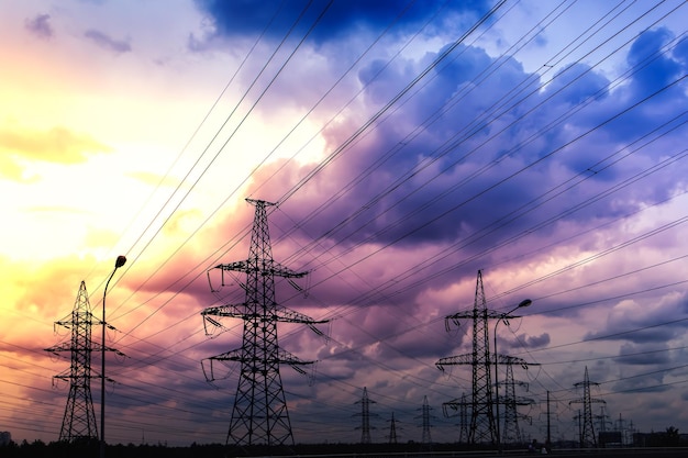 Silhueta de torres elétricas de alta tensão em um fundo por do sol