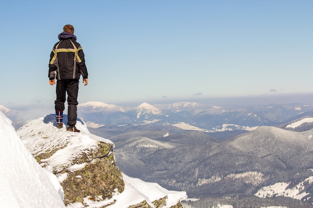 Silhueta de turista sozinho em pé no topo da montanha de neve, apreciando a vista