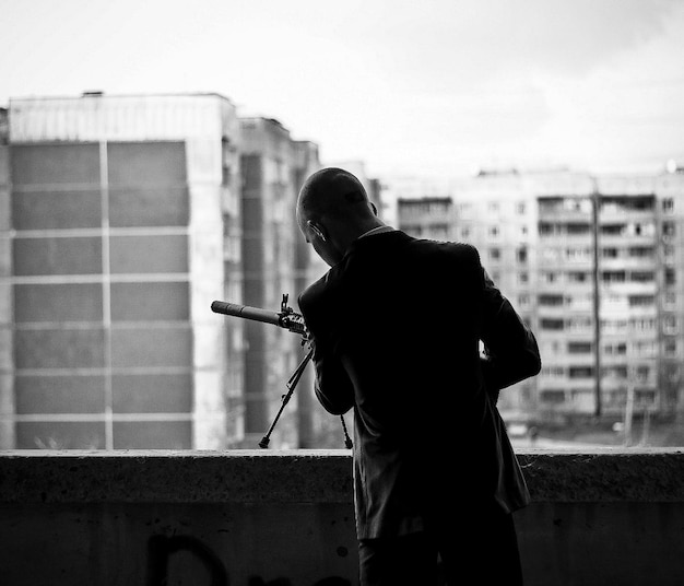 Silhueta de um assassino de terno ou um assassino com uma arma por dia. espingarda de atirador. foto preto e branco