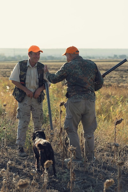 Silhueta de um caçador com uma arma nos juncos contra o sol uma emboscada para patos com cães