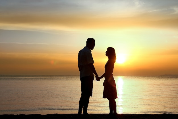 Silhueta de um casal amoroso feliz ao pôr do sol na praia