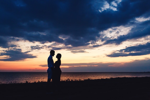 Silhueta de um casal apaixonado por um lindo pôr do sol no céu e no mar