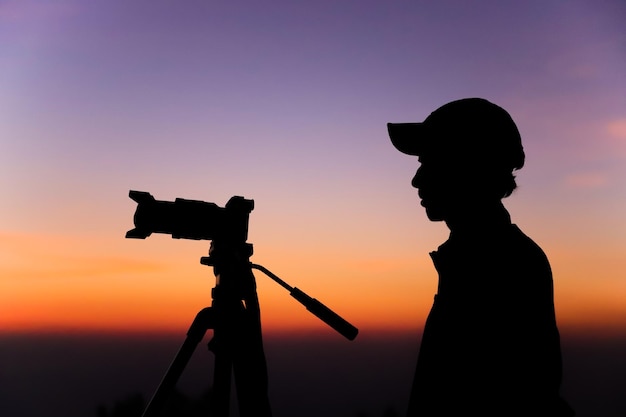 Silhueta de um fotógrafo com tripé Jovem indiano tirando foto com sua câmera