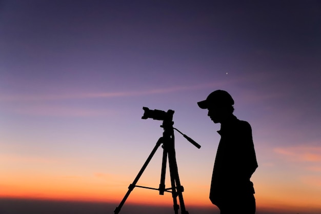 Silhueta de um fotógrafo com tripé Jovem indiano tirando foto com sua câmera