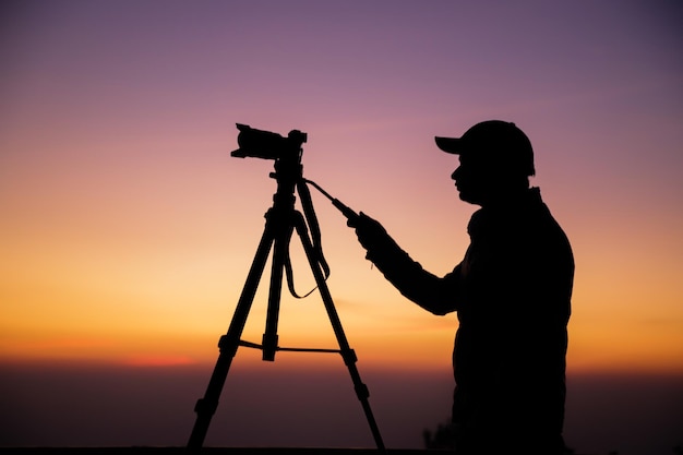 Silhueta de um fotógrafo com tripé Jovem indiano tirando foto com sua câmera