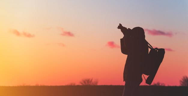 Foto silhueta de um fotógrafo em um fundo por do sol com um tripé