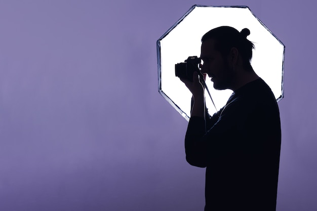 Silhueta de um fotógrafo, segurando a câmera na frente de um flash