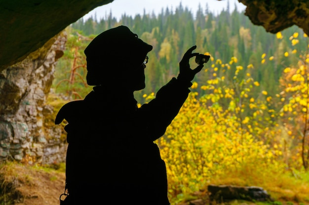 Silhueta de um geólogo examinando uma amostra mineral encontrada em uma caverna