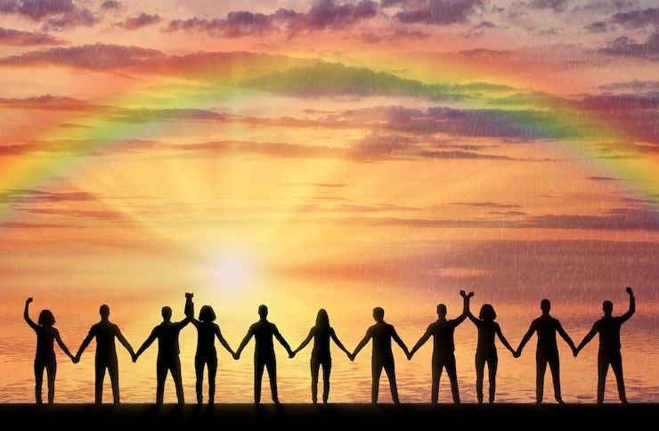 Foto silhueta de um grupo de pessoas felizes, de mãos dadas à beira-mar ao pôr do sol com um arco-íris. o conceito de assistência mútua e apoio nas pessoas
