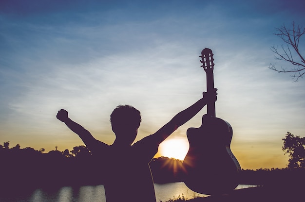 Silhueta de um guitarrista nas sombras na luz do sol, conceito de silhueta.