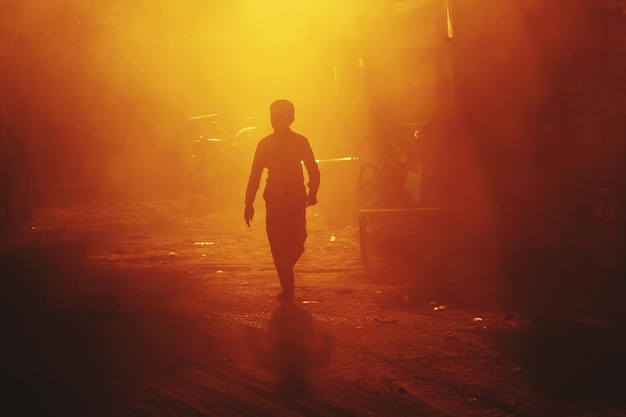 Silhueta de um homem a caminhar pela estrada à noite.