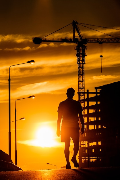 Silhueta de um homem caminhando sobre uma ponte ao pôr do sol.