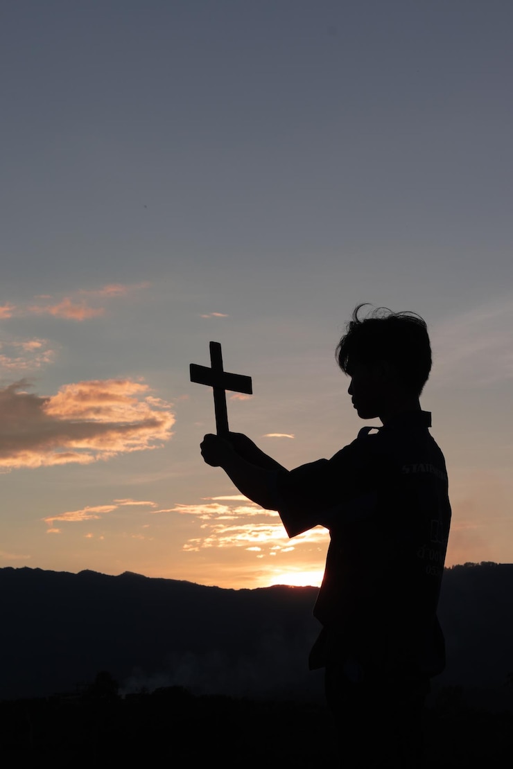Foto silhueta de um homem com os braços levantados contra o céu durante o pôr do sol