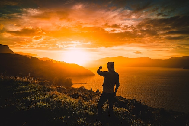 Foto silhueta de um homem de pé na montanha contra o céu durante o pôr do sol