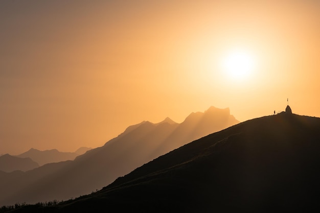 Silhueta de um homem junto a uma bandeira nos Alpes suíços ao pôr do sol