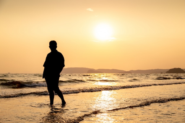 Silhueta de um homem na praia ao pôr do sol.