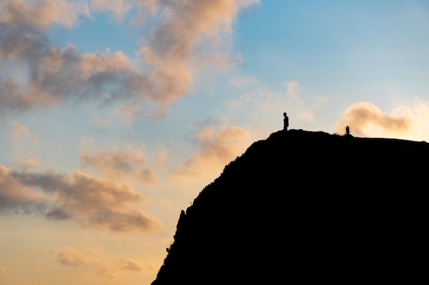 Silhueta de um homem olhando para o horizonte de um penhasco em um pôr do sol