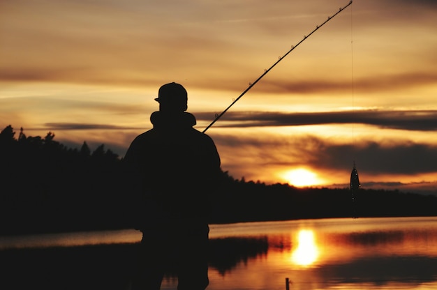 Silhueta de um homem pescando ao pôr-do-sol