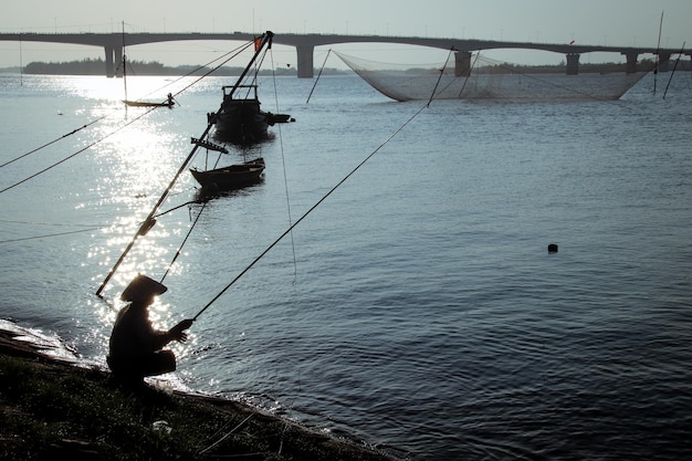 Foto silhueta de um homem pescando no mar contra o céu