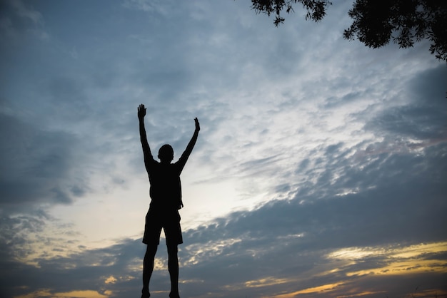 Foto silhueta de um homem pulando de felicidade por do sol.