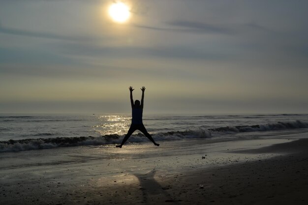 Silhueta de um homem pulando na praia ao pôr do sol Oceano Pacífico Peru