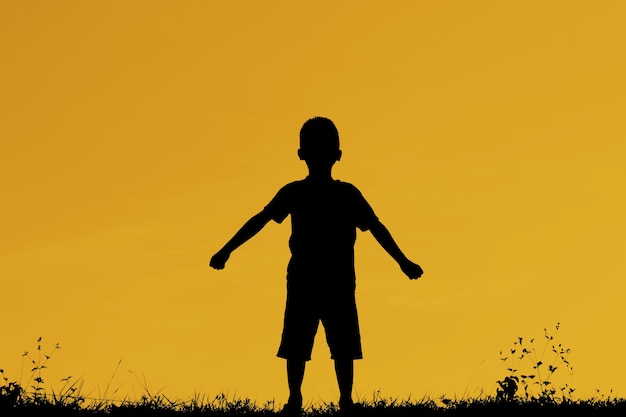 Foto silhueta de um menino brincando contra o céu durante o pôr do sol