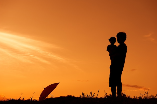 Silhueta de um pai e filho jogando ao ar livre ao pôr do sol