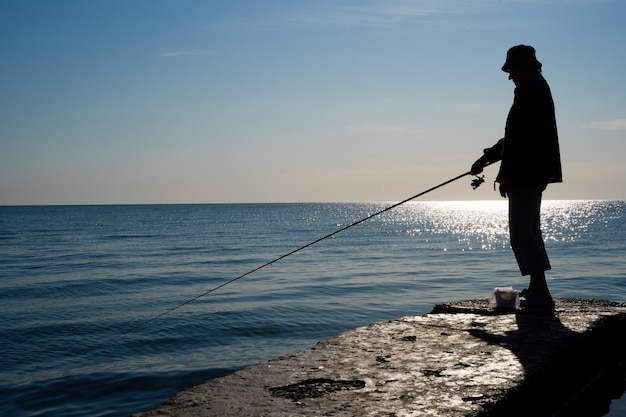 Silhueta de um pescador pega peixe no mar