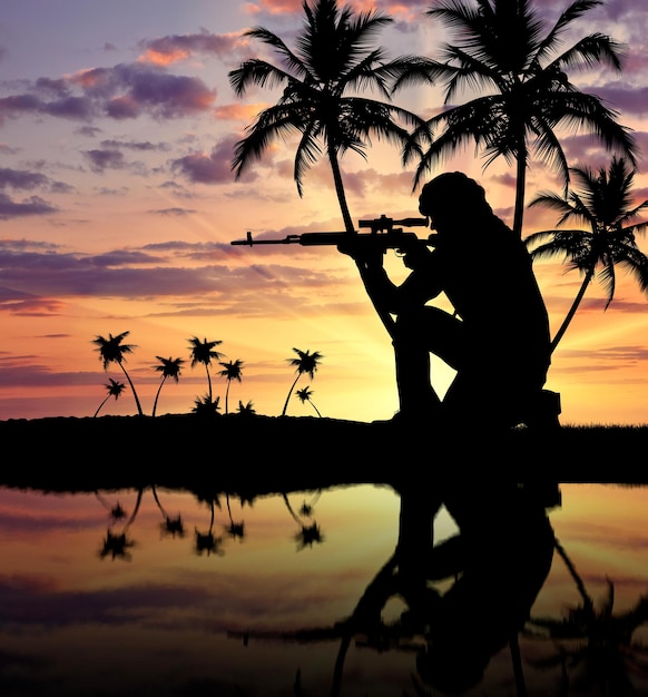 Silhueta de um terrorista com uma arma no contexto de um pôr do sol com palmeiras e reflexo na água