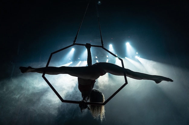 Silhueta de uma acrobata aérea feminina no palco do circo com luzes especiais