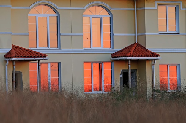 Silhueta de uma árvore e o reflexo da luz do sol nascente nas janelas das casas ao amanhecer do mar. uma visão incomum das coisas comuns