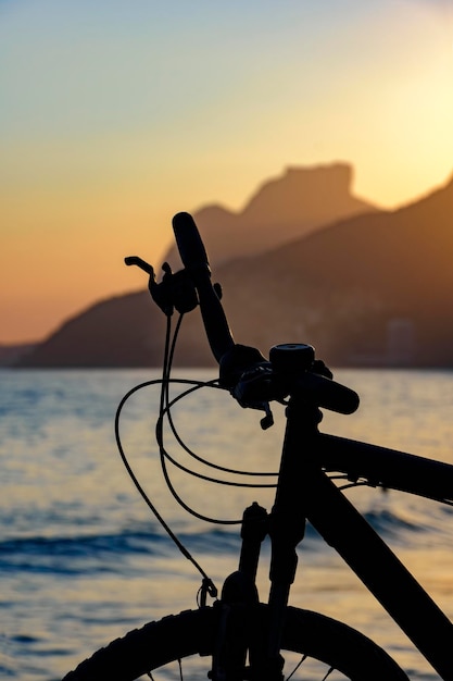 Foto silhueta de uma bicicleta na praia de ipanema ao pôr do sol