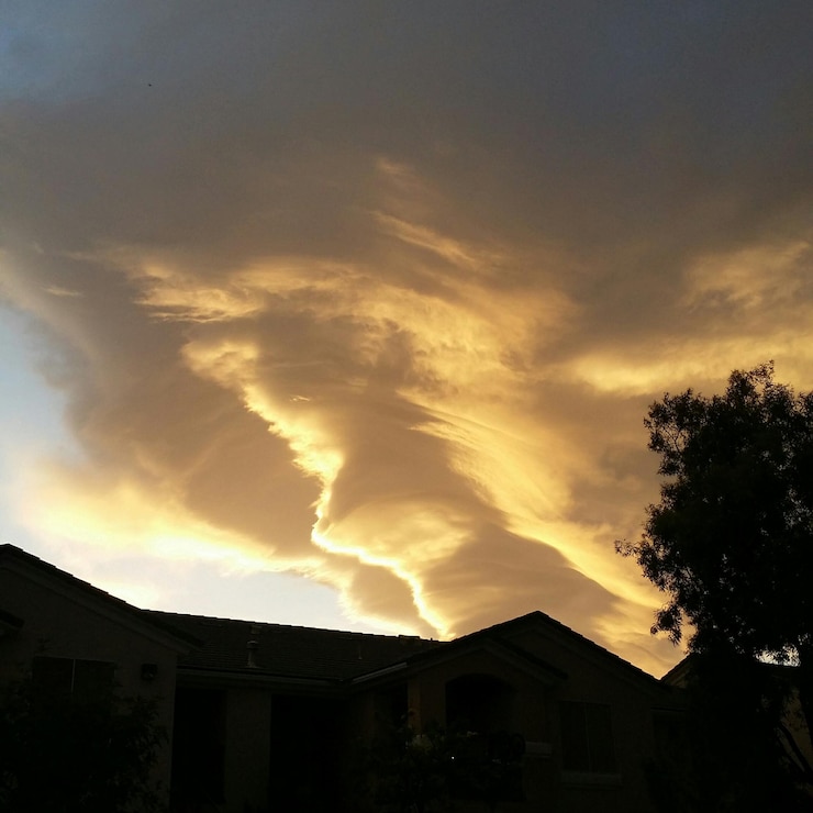 Foto silhueta de uma casa por uma árvore contra um céu nublado durante o pôr do sol