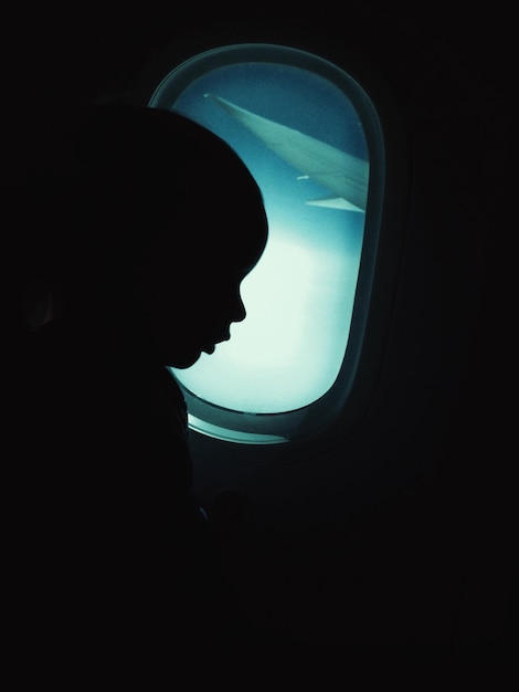 Foto silhueta de uma criança sentada num avião