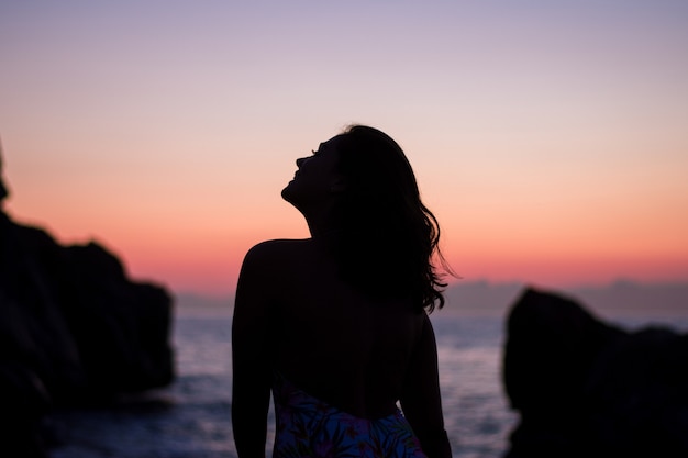Silhueta de uma garota na praia durante o nascer do sol