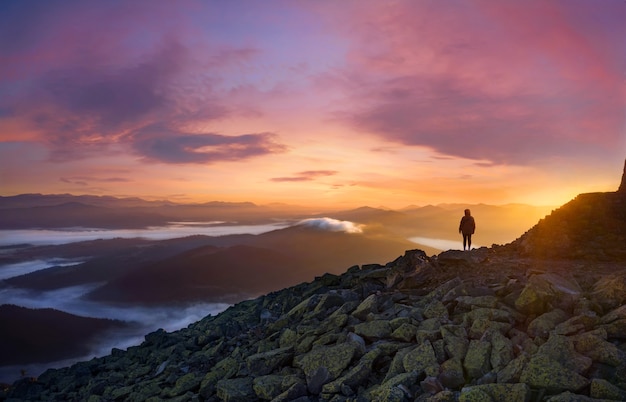 Foto silhueta de uma garota no pico de uma montanha pela manhã ao nascer do sol.