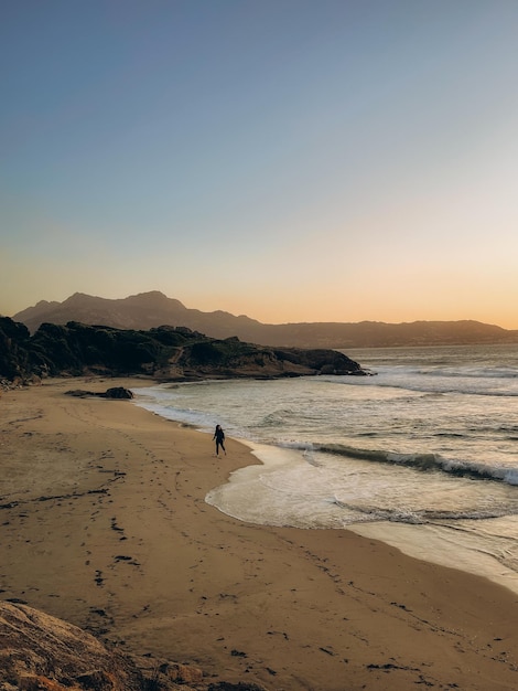 Silhueta de uma mulher na praia ao pôr-do-sol na Córsega, França