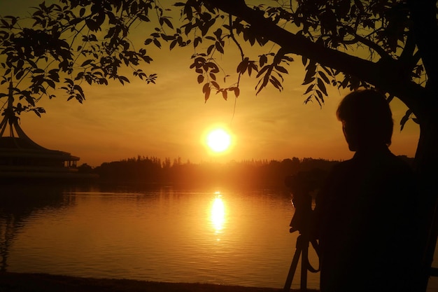 Silhueta de uma pessoa assistindo e fotografando o belo nascer do sol